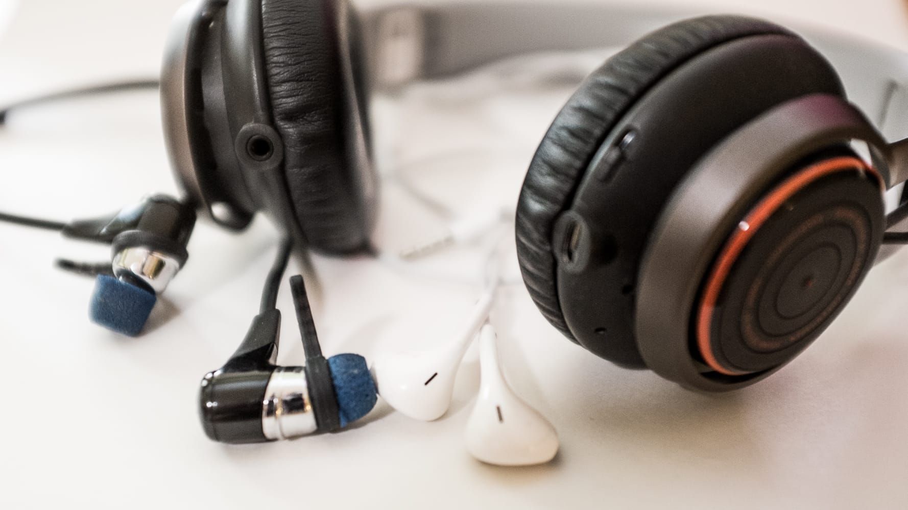 Jabra Revo and BlueBuds X with Apple EarPods for scale.